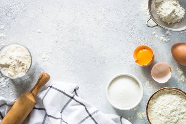 Baking ingredients. Food cooking background. Flour, sugar, eggs and others at light stone table. Top view with copy space.