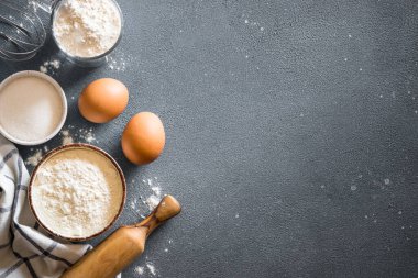 Mavi taş masada fırın arka planı. Un, şeker, yumurta ve çatal bıçak. Kopyalama alanı olan üst görünüm.