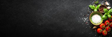 Sebzeler, otlar ve baharatlarla dolu siyah taş masada yemek. Uzun pankart biçimi.