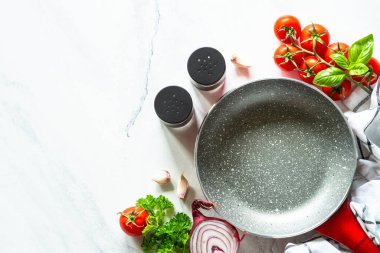 Mutfak masasında tava ya da tava, sebze ve otlar beyaz mermer masada. Kopyalama alanı olan üst görünüm.