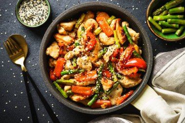 Chicken stir fry with vegetables at stone background. Flat lay image.