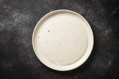 White craft plate at black table. Top view image with copy space.