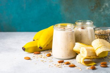 Almond banana smoothie with oat flakes in glass jars.