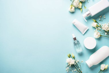 Natural cosmetic products. Cream, serum, tonic with green leaves and flowers. Skin care concept. Flat lay image with copy space.