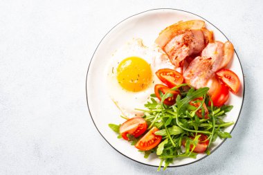 Healthy breakfast or lunch. Becon, eggs and fresh salad. Top view on white.