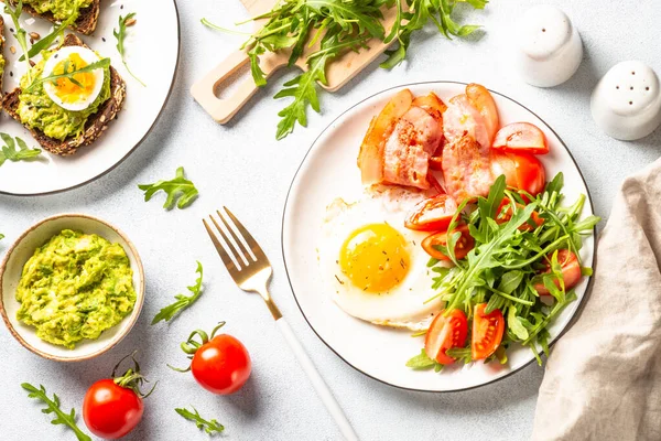 Healthy breakfast or lunch. Becon, eggs, toast with avocado and fresh salad. Top view on white.