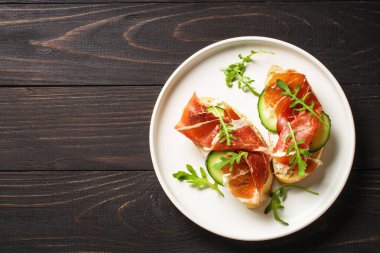 Aperatif crostini, krem peynirli sandviç, prosciutto, salatalık ve roka. Düz yatıyordu.