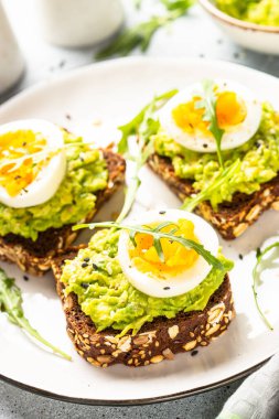 Avocado sandwich. Whole grain bread with avocado and boiled eggs with arugula. Close up image.