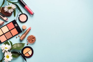 Make up products on blue background. Cream, powder, shadow, brushes. Flat lay image with copy space.