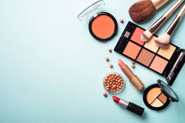 Make up professional cosmetics on blue background. Powder, lipstick, shadow, brushes. Flat lay with copy space.