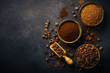 Roasted coffee beans, ground coffee and instant coffee in bowls at dark background. Flat lay image.
