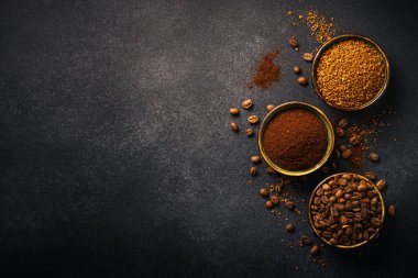 Roasted coffee beans, ground coffee and instant coffee in bowls at dark background. Top view image.