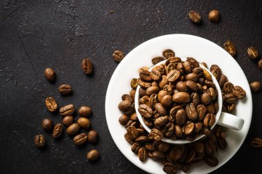 Coffee cup. Roasted coffee beans in white cup at dark table. Top view image.