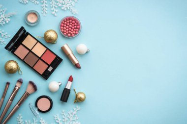 Make up products and winter decorations on blue background. Winter cosmetic. Flat lay image with copy space.