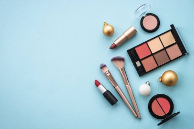 Make up products and winter decorations on blue background. Winter cosmetic. Flat lay image with copy space.