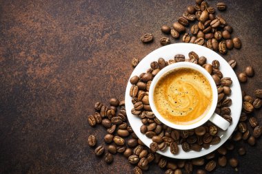 Cup of coffee and roasted coffee beans at dark table . Top view with copy space.