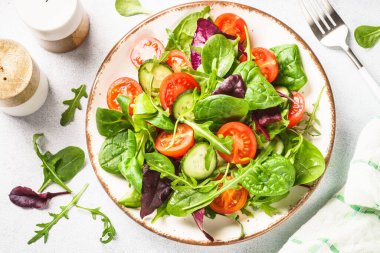 Salad from green leaves and vegetables. Fresh green salad in white plate. Top view.