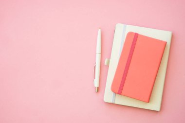 Pink notepad and pan at pink office table. Flat lay.