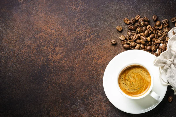 暗いテーブルでコーヒー豆とコーヒー豆の袋のカップ コピースペース付きのトップビュー画像 — ストック写真