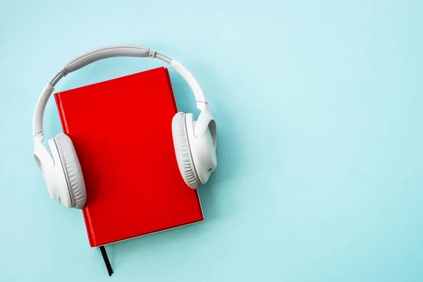 Audio books concept. Headphones and books on blue background. Listen, study, podcast.