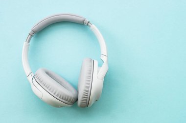 Wireless Headphones on blue background. Flat lay with copy space.