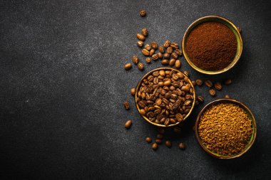 Roasted coffee beans, ground coffee and instant coffee in bowls at dark background. Top view image.