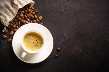 Cup of coffee espresso and bag of coffee beans at dark table . Top view with copy space.