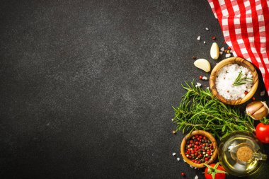 Ingredients for cooking on black stone kitchen table. Herbs, spices and vegetables. Flat lay.
