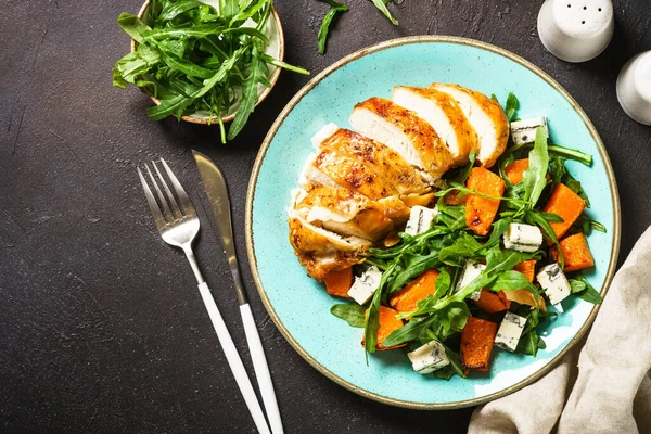Warm salad with baked chicken breast, pumpkin, blue cheese and arugula. Dash diet, keto diet meal. Top view image.