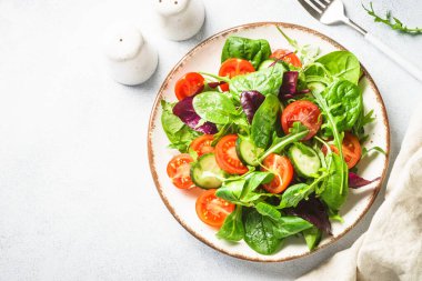 Salad from green leaves and vegetables. Fresh green salad in white plate. Top view.