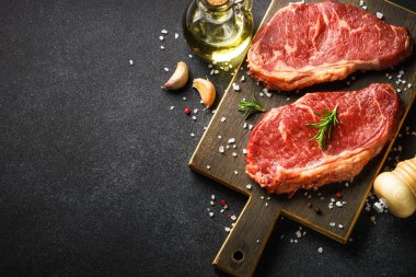 Beef steak with spices. Raw beef meat at black. Top view image.