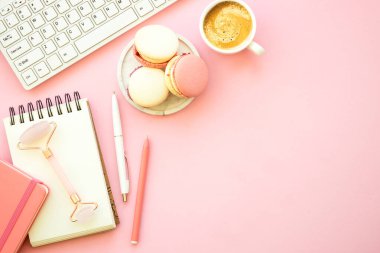 Home office workspace. Pink flat lay office desk with keyboard, notebook and coffee cup..