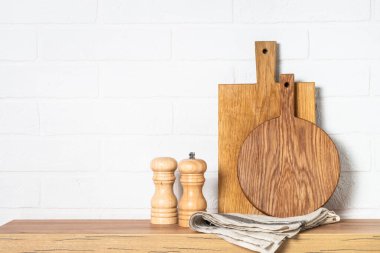 Wooden cutting boards on the kitchen wooden table near white wall.