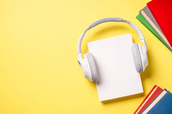 Audio book. Headphones and books at yellow background. Flat lay image with copy space.