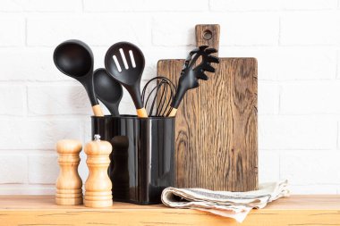 Kitchen utensils. Cooking tools with wooden cutting boards, oil and shaker at white modern kitchen interior.