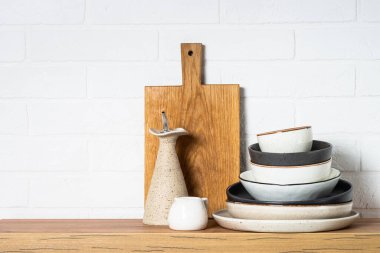 Kitchen table, kitchen utensils, plates, bowls and wooden cutting board, whiye background. Modern kitchen interior.