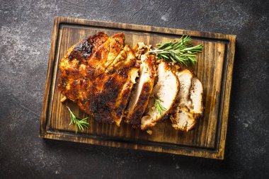 Baked ham, glazed meat with herbs on wooden cutting board. Top view on black background.