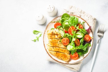 Green salad with chicken fillet on white. Diet food, healthy nutrition. Top view with copy space.