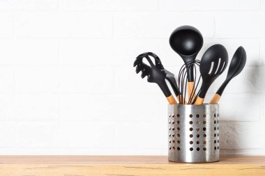 Mutfak aletleri, yemek pişirme aletleri beyaz duvarın yanındaki metal kabın içinde..