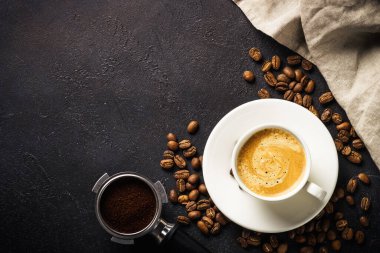 Kahve fincanı, kahve çekirdeği ve kara masada filtre tutacağı. Kopyalama alanı olan en üst görüntü.