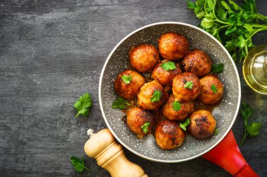 Karanlık masadaki tavada domates soslu köfte. Düz görünüm.