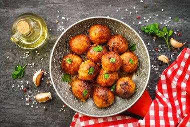 Karanlık masadaki tavada domates soslu köfte. Düz görünüm.