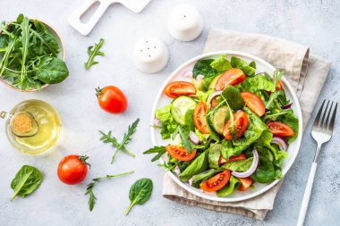 Yapraklı, sebzeli ve zeytinyağlı taze yeşil salata. Işık taşı masadaki en üst görünüm.