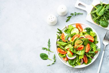 Yapraklı ve sebzeli taze yeşil salata. Taş masada kopyalama alanı olan üst görünüm.