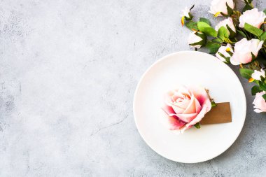 Masa düzenleme, beyaz tabak ve pembe çiçeklerle servis edilen şenlik masası. Kopyalama alanı olan beyaz görünüm.