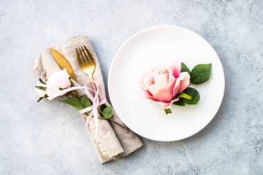 Masa düzenleme, beyaz tabak, çatal bıçak ve çiçeklerle servis edilen şenlik masası. Üst görünüm beyaz.