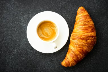 Siyah arka planda kruvasan ve kahve. Fransız pastası, fırın, kahvaltı. Üst görünüm.