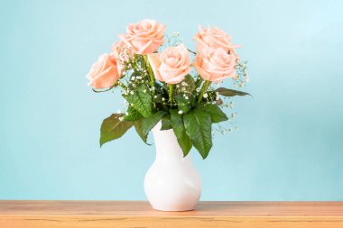 Pink rose flowers in white vase at blue background. clipart