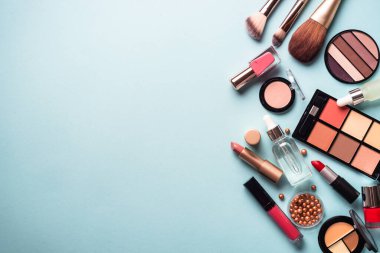 Make up professional cosmetics on blue background. Powder, lipstick, shadow, brushes. Flat lay with copy space.