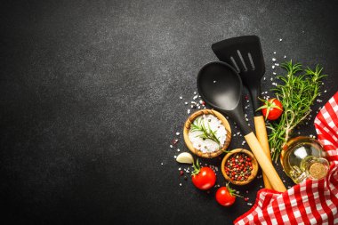 Food background on black. Herbs, spices and utensil for healthy cooking. Top view with copy space.